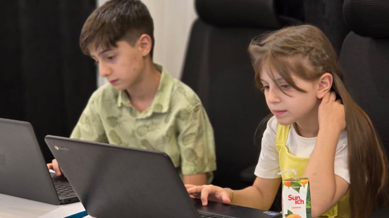 Two students writing code on laptops